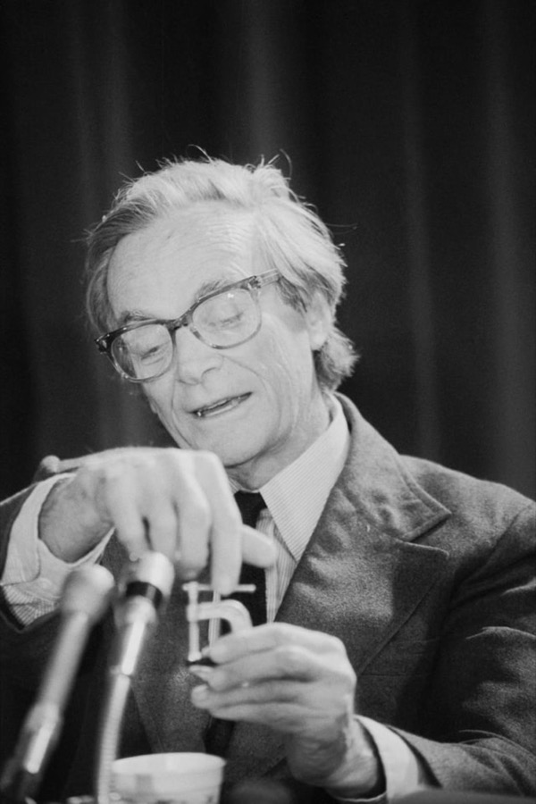 Richard Feynman at a lectern, adjusting a microphone