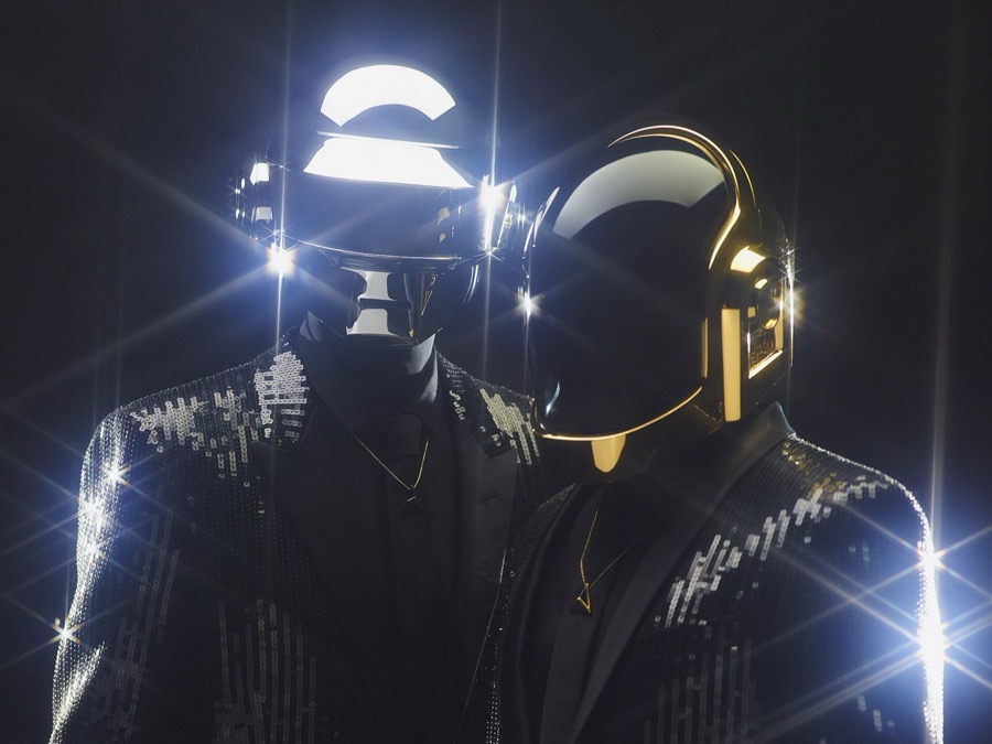 Daft Punk on stage in their robot helmets, lit from behind