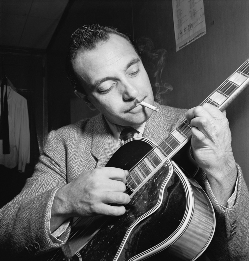 Django Reinhardt playing guitar, a cigarette in his mouth